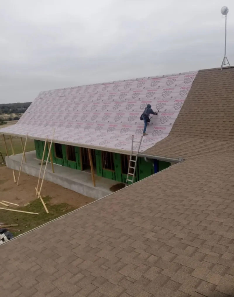 Worker preparing underlayment for a metal roof installation in Westport